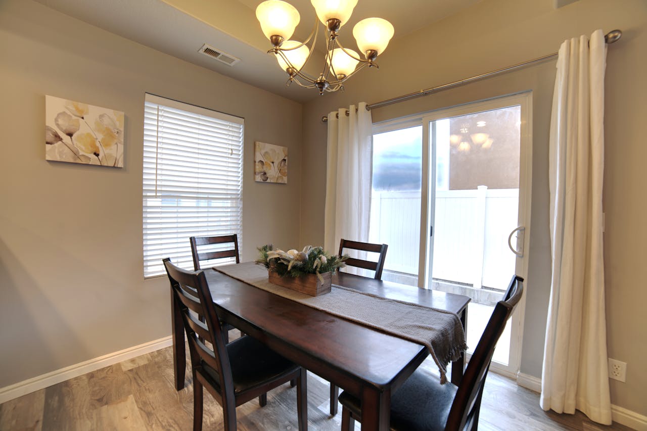 A cozy dining room featuring a wooden table, chairs, and an elegant chandelier.